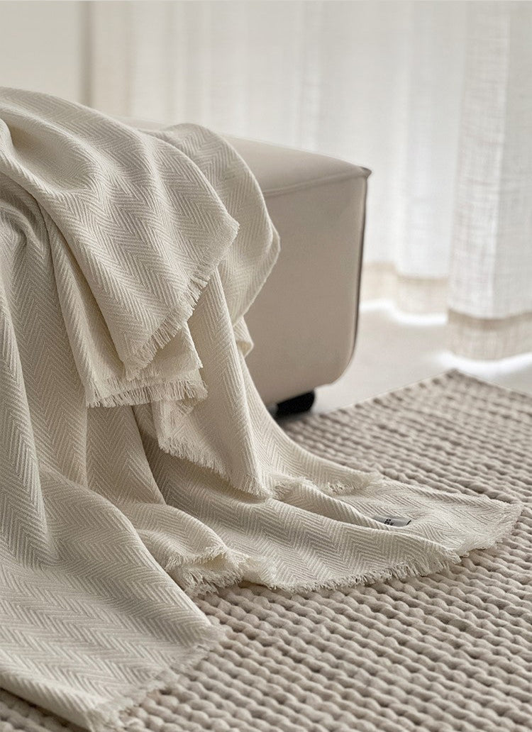 Classic witte Herringbone plaid met franjes op de bank, gemaakt van luxe wolmix, met een subtiel visgraatpatroon.