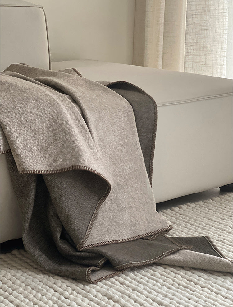 Close-up van de TWO TONE deken in bruin en beige, prachtig gedrapeerd over een bank met een nette en stijlvolle afwerking.