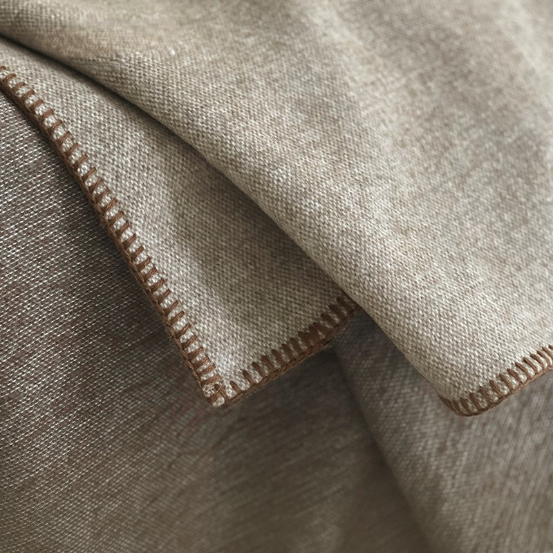 Close-up van de rand van de Two-tone deken met een fijne stiksels in beige en bruin.