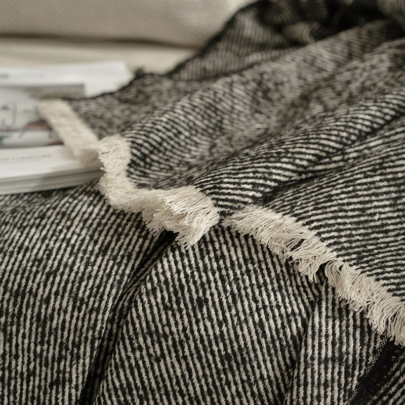 Close-up van de franjes van de zwarte plaid op de bank, die de fijne textuur en luxe uitstraling tonen.