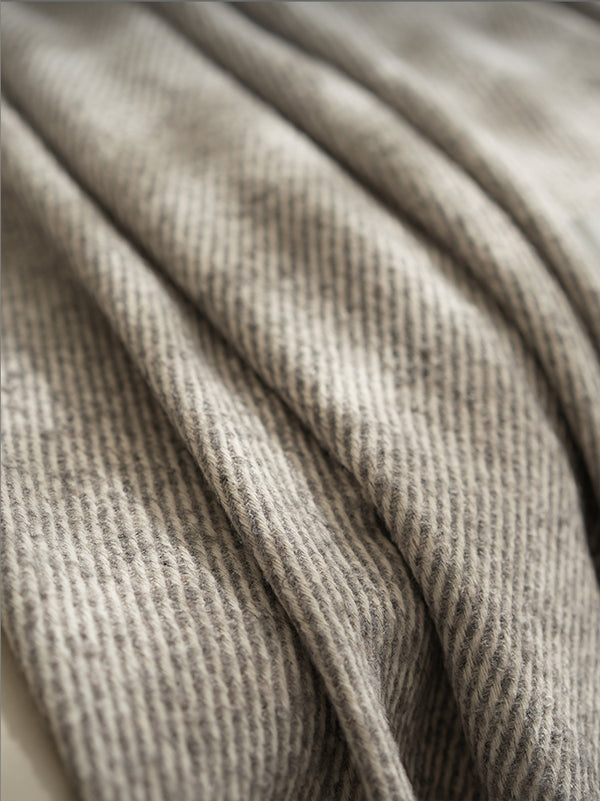 Close-up van een grijze beige  plaid met een fijn geweven patroon, met subtiele textuurdetails voor een luxe uitstraling
