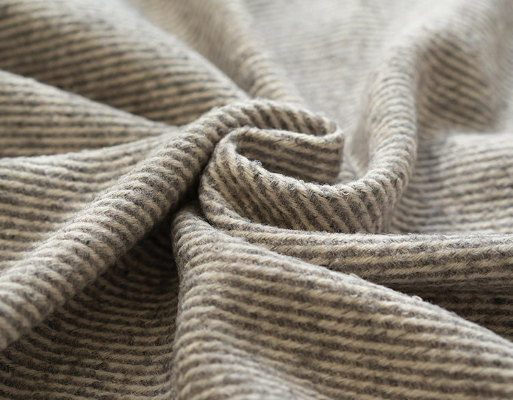 Close-up van een grijze beige  plaid met een fijn geweven patroon, met subtiele textuurdetails voor een luxe uitstraling